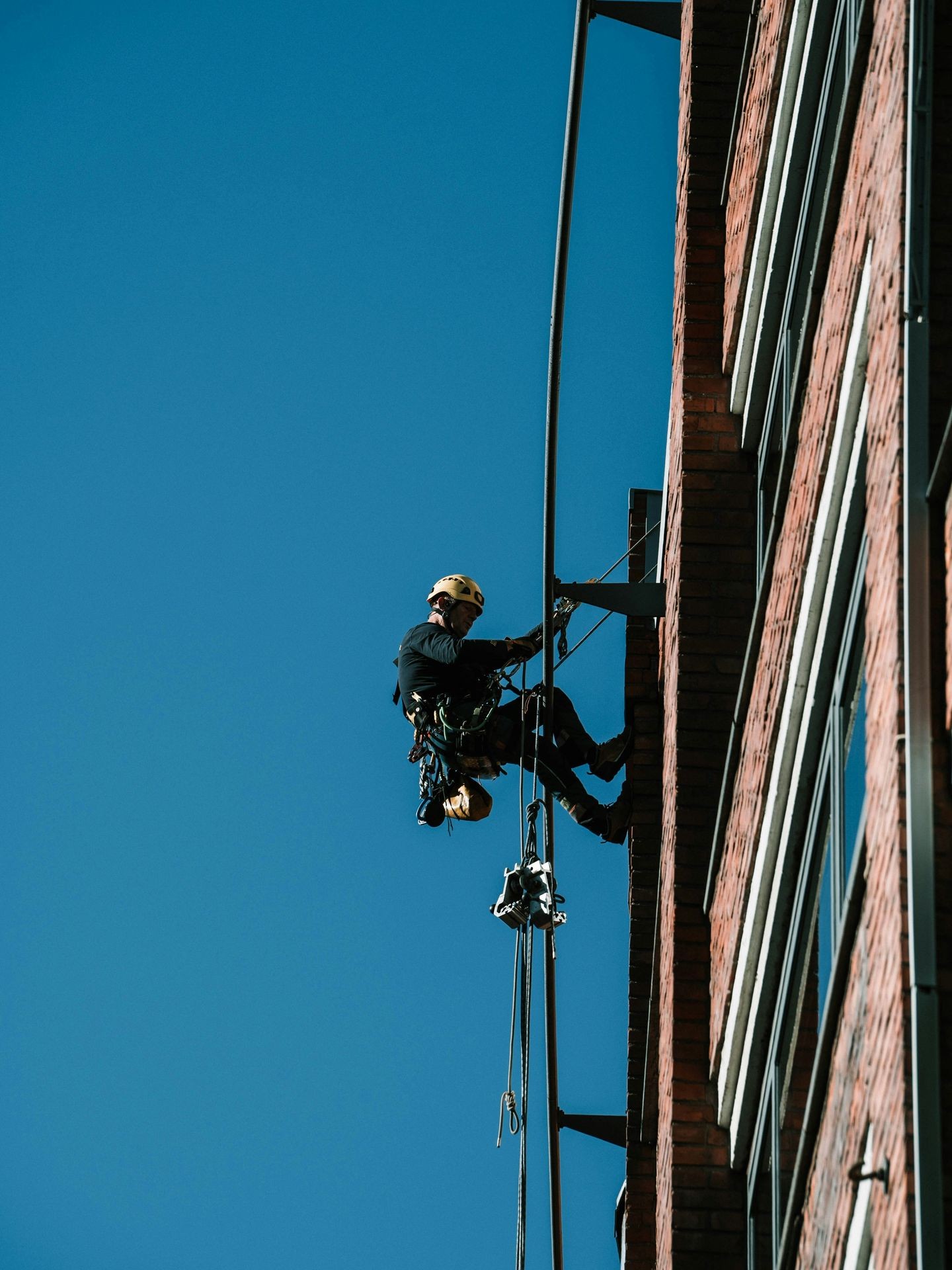 Professional rope access technician performing high-rise building maintenance